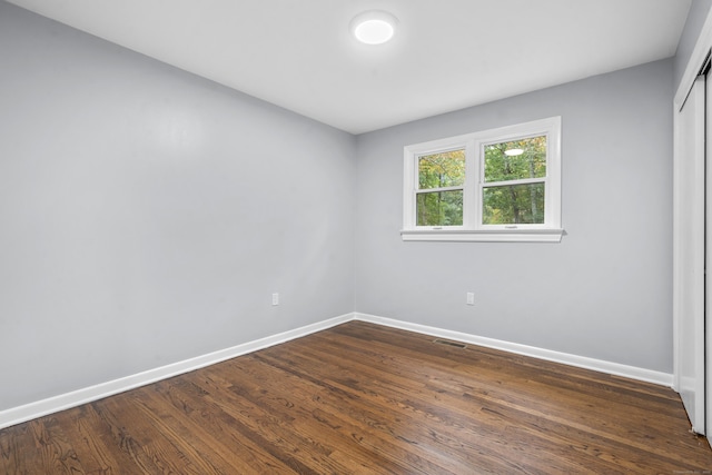 empty room featuring baseboards, visible vents, and dark wood-type flooring