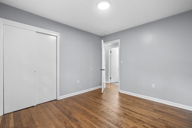 unfurnished bedroom with baseboards, wood finished floors, and a closet