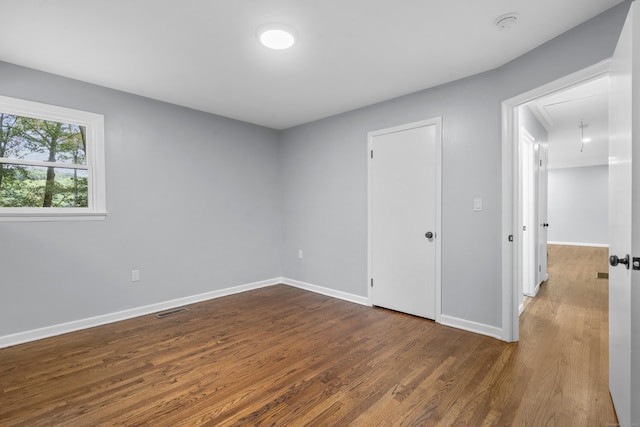 spare room featuring baseboards, visible vents, dark wood-style floors, and attic access