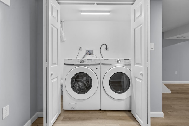 laundry room featuring laundry area, washer and clothes dryer, baseboards, and wood finished floors