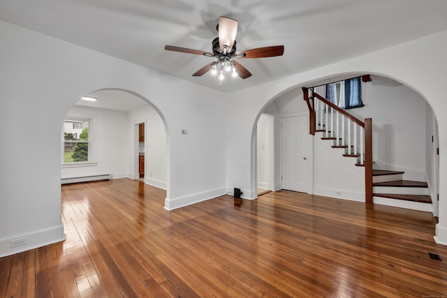 291 E St, New Britain, CT 06051 - spare room featuring hardwood / wood-style flooring, stairs, a baseboard radiator, arched walkways, and a ceiling fan