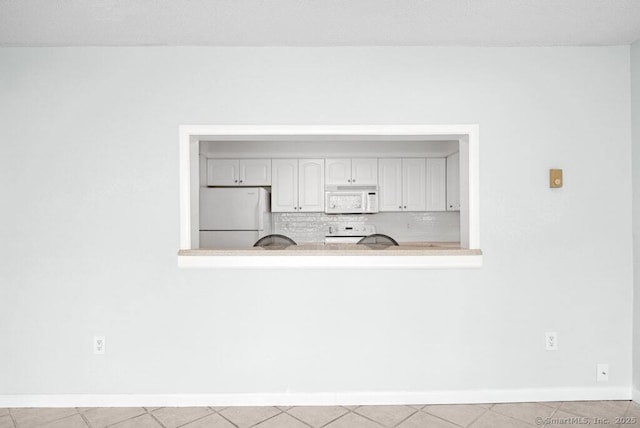 interior details featuring baseboards, white appliances, decorative backsplash, light countertops, and white cabinets