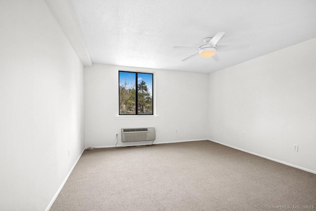 empty room featuring a wall mounted air conditioner, a textured ceiling, carpet floors, a ceiling fan, and baseboards