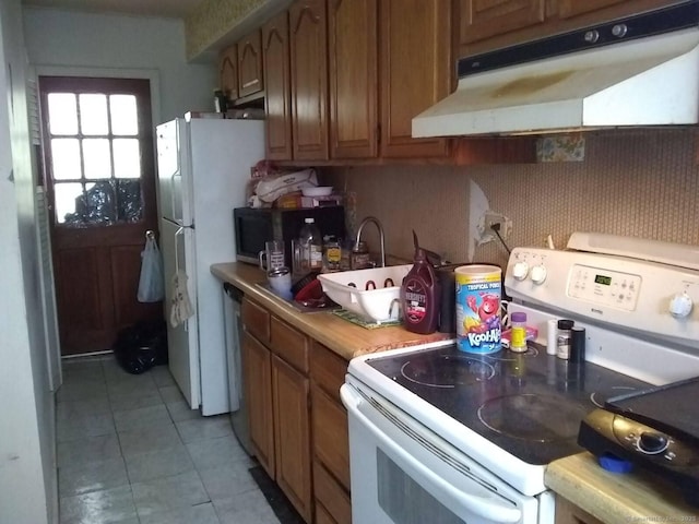 kitchen with brown cabinets, light countertops, under cabinet range hood, white appliances, and light tile patterned flooring