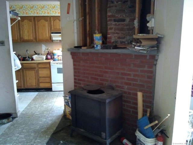 interior space with a sink, white electric range oven, brown cabinetry, and under cabinet range hood
