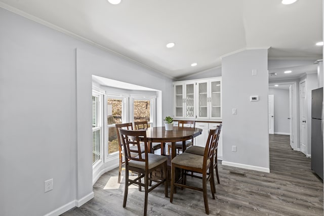 dining room with visible vents, ornamental molding, baseboards, dark wood finished floors, and vaulted ceiling
