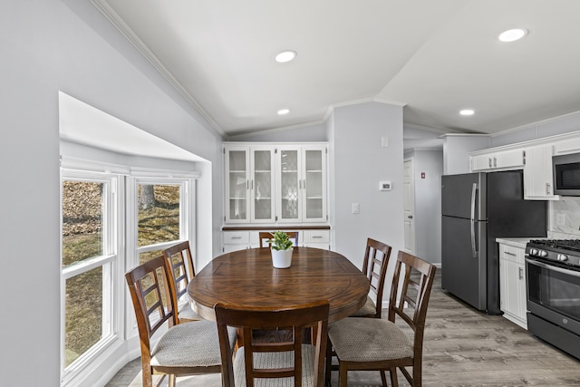 dining room featuring crown molding, recessed lighting, vaulted ceiling, and light wood-style flooring