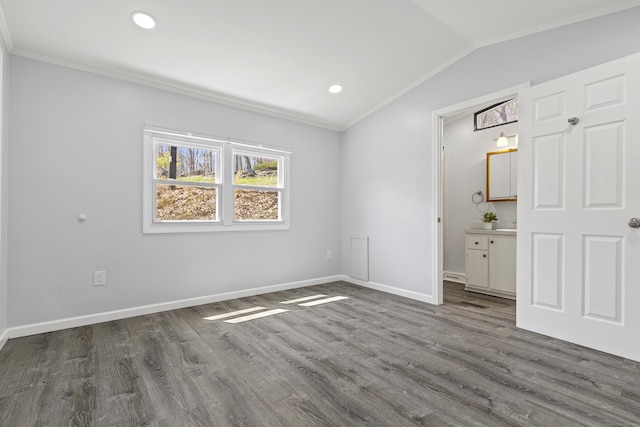 unfurnished bedroom with dark wood-type flooring, ornamental molding, baseboards, and vaulted ceiling