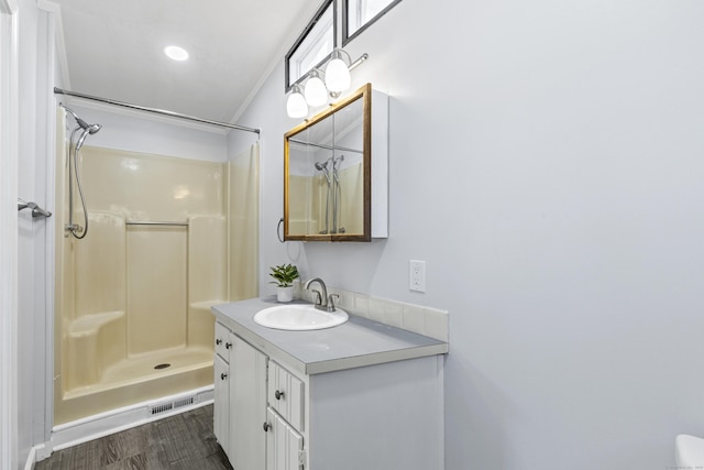 full bathroom featuring visible vents, crown molding, walk in shower, wood finished floors, and vanity