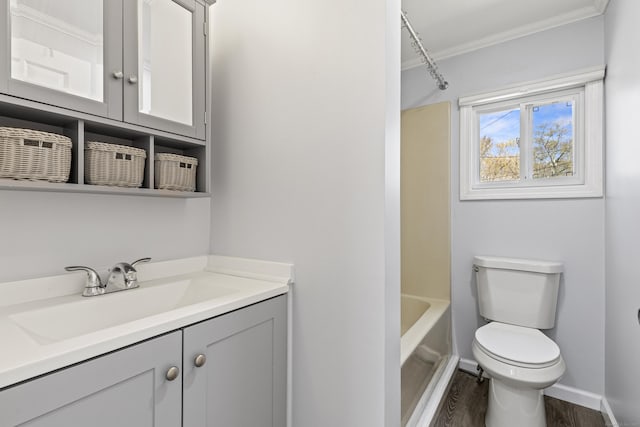 bathroom featuring vanity, toilet, baseboards, wood finished floors, and ornamental molding