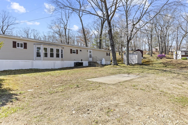rear view of house featuring an outdoor structure, central AC, a shed, and entry steps