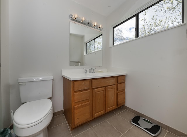 bathroom with toilet, tile patterned floors, baseboards, and vanity