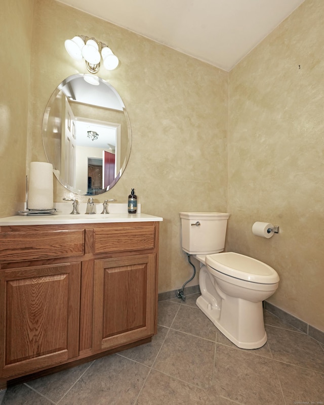 half bathroom with toilet, tile patterned floors, baseboards, and vanity
