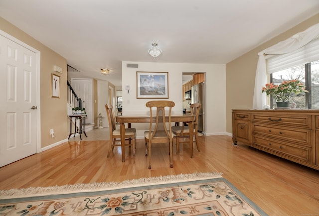 dining area with visible vents, stairs, light wood finished floors, and baseboards