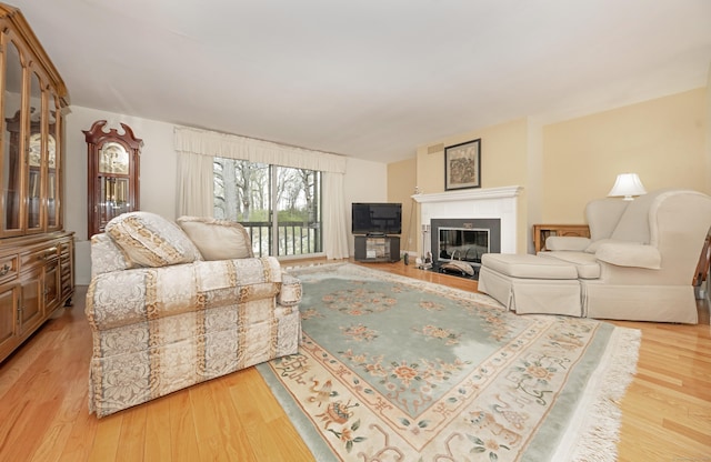 living area with light wood-style flooring and a glass covered fireplace