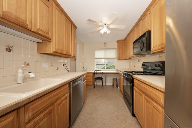 kitchen with light countertops, a sink, backsplash, light tile patterned floors, and black appliances