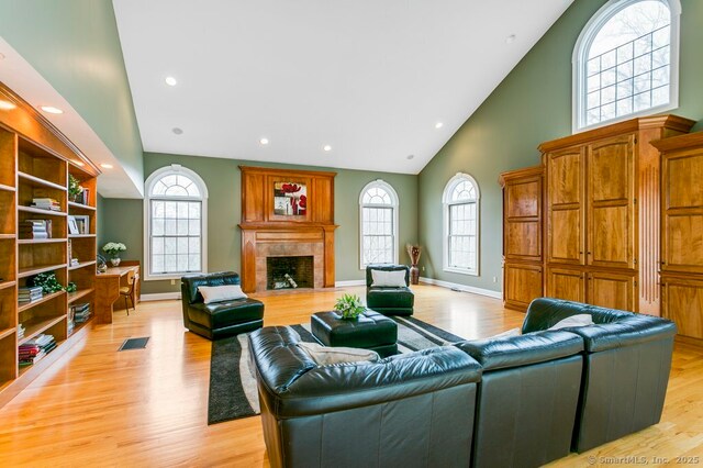 32 Village Dr, East Lyme, CT 06333 - living area with high vaulted ceiling, light wood-style flooring, healthy amount of natural light, a premium fireplace, and recessed lighting