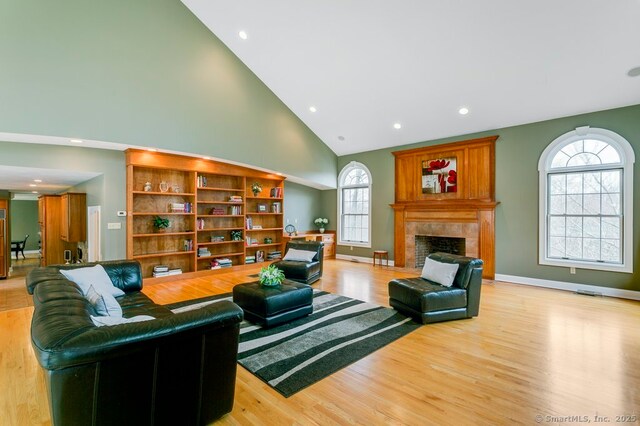 32 Village Dr, East Lyme, CT 06333 - living area with high vaulted ceiling, recessed lighting, light wood-style flooring, a tile fireplace, and baseboards