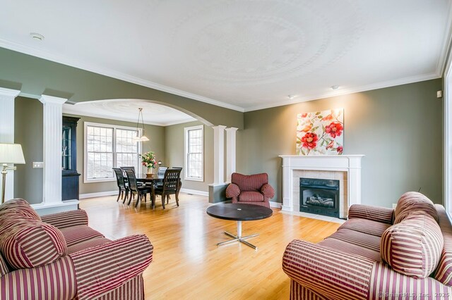 32 Village Dr, East Lyme, CT 06333 - living room with decorative columns, light wood-style floors, arched walkways, a fireplace, and baseboards