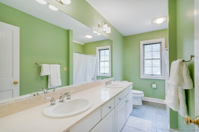 32 Village Dr, East Lyme, CT 06333 - bathroom featuring healthy amount of natural light, double vanity, baseboards, and toilet