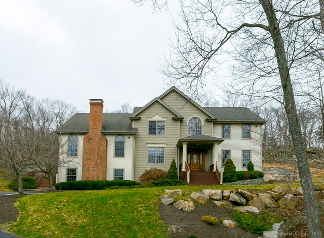 32 Village Dr, East Lyme, CT 06333 - view of front facade featuring a chimney, a front lawn, and a shingled roof