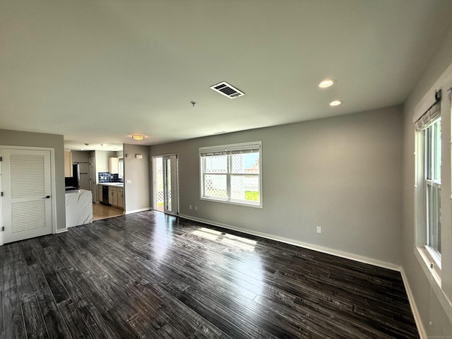 unfurnished living room with dark wood-style flooring, healthy amount of natural light, baseboards, and recessed lighting
