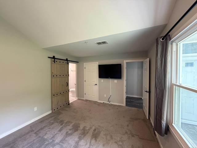 unfurnished living room with carpet flooring, baseboards, and a barn door