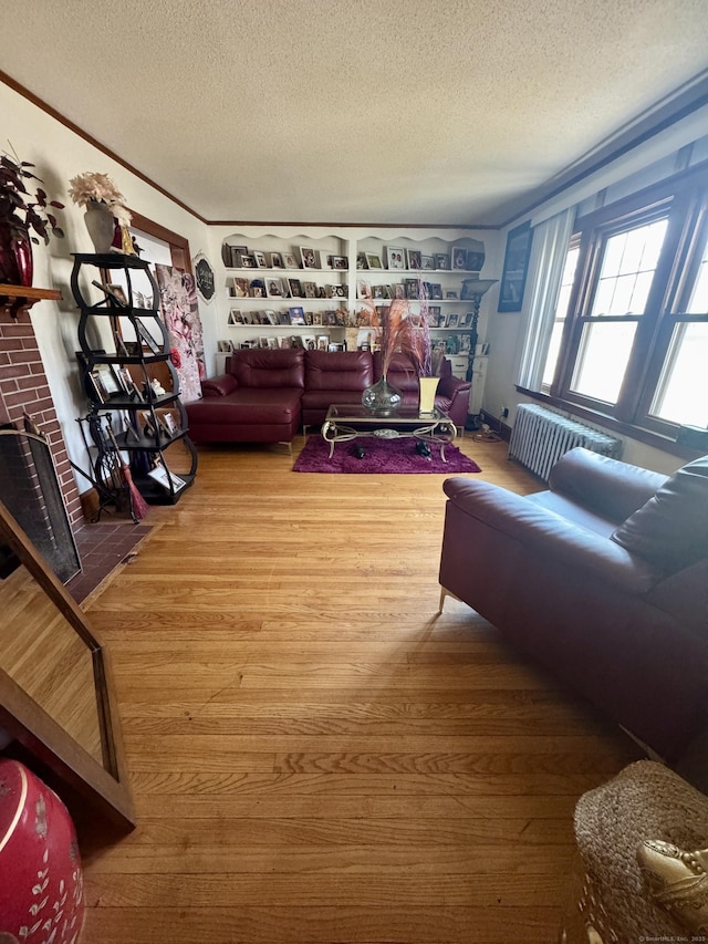 572 Forbes St, East Hartford, CT 06118 - living area with radiator, a fireplace, a textured ceiling, and wood finished floors