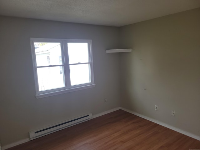 spare room featuring baseboards, baseboard heating, and wood finished floors