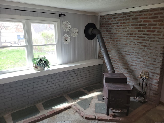 interior space with a healthy amount of sunlight, a wood stove, and brick wall