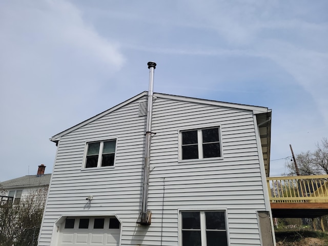 view of side of property featuring an attached garage and a deck
