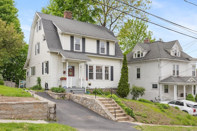 colonial inspired home featuring a chimney and a shingled roof