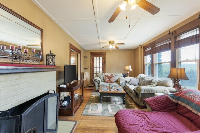 living area with radiator, ceiling fan, wood finished floors, and a fireplace
