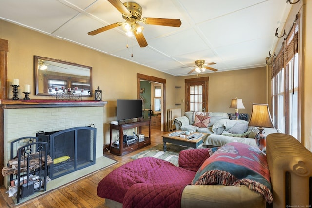 living area featuring healthy amount of natural light, wood-type flooring, a ceiling fan, and coffered ceiling
