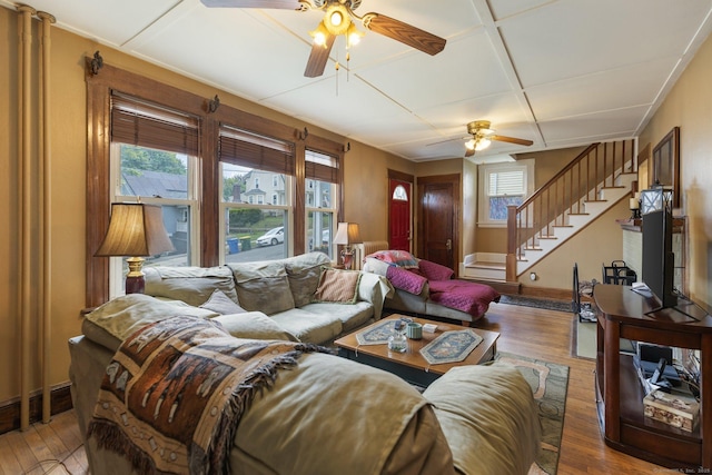 living room featuring ceiling fan, hardwood / wood-style floors, stairway, and baseboards