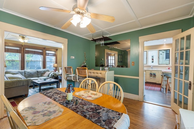dining area with a ceiling fan, wood finished floors, crown molding, and baseboards