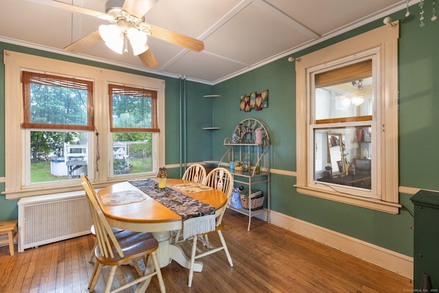 dining area with hardwood / wood-style floors, ceiling fan, ornamental molding, baseboards, and radiator