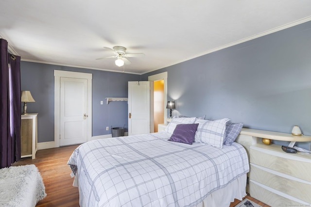 bedroom with baseboards, wood finished floors, ceiling fan, and crown molding