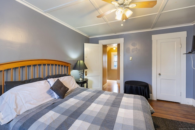 bedroom featuring ceiling fan, baseboards, wood finished floors, coffered ceiling, and crown molding