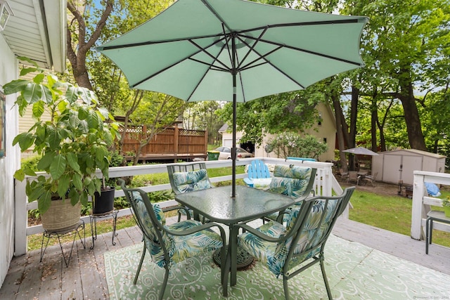 view of patio featuring outdoor dining area, a shed, a wooden deck, and an outdoor structure