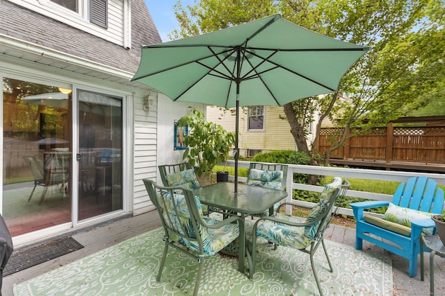 view of patio featuring a deck, outdoor dining area, and fence