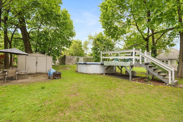 view of grassy yard with a storage unit, an outbuilding, a covered pool, stairs, and a deck