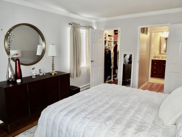 bedroom featuring a closet, ornamental molding, wood finished floors, a spacious closet, and a baseboard radiator
