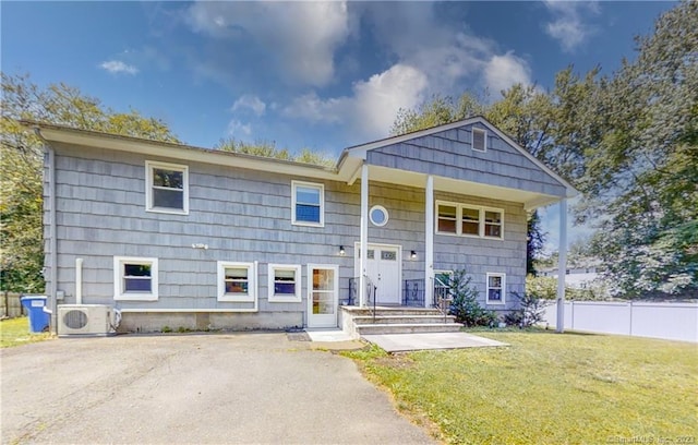 raised ranch with fence, ac unit, and a front yard