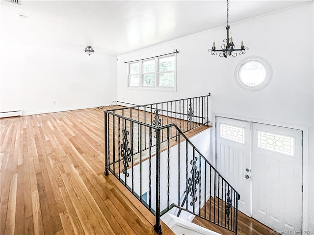 stairway with baseboard heating, a chandelier, wood finished floors, and visible vents