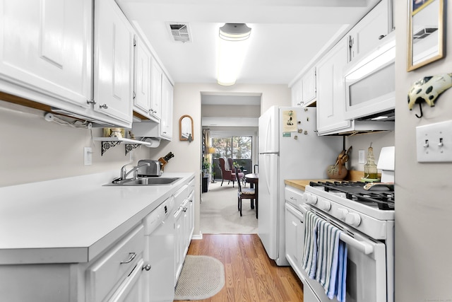 kitchen featuring white appliances, light countertops, light wood-style flooring, white cabinetry, and a sink
