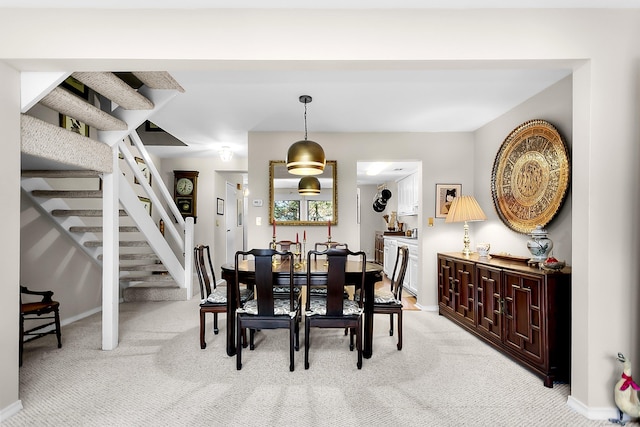 dining room featuring light carpet, stairway, and baseboards