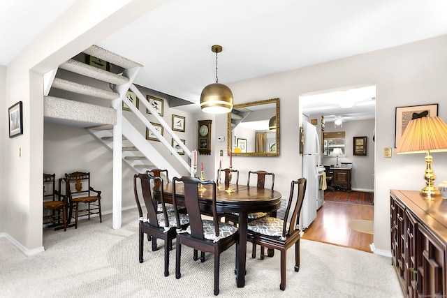 dining area featuring stairs, baseboards, a ceiling fan, and carpet floors