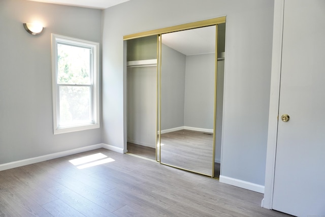 61 Forest St, Naugatuck, CT 06770 - unfurnished bedroom featuring multiple windows, a closet, and wood finished floors