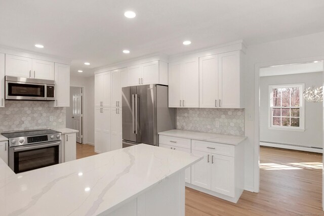 1510 Congress St, Fairfield, CT 06825 - kitchen featuring appliances with stainless steel finishes, a baseboard heating unit, white cabinetry, light wood finished floors, and backsplash